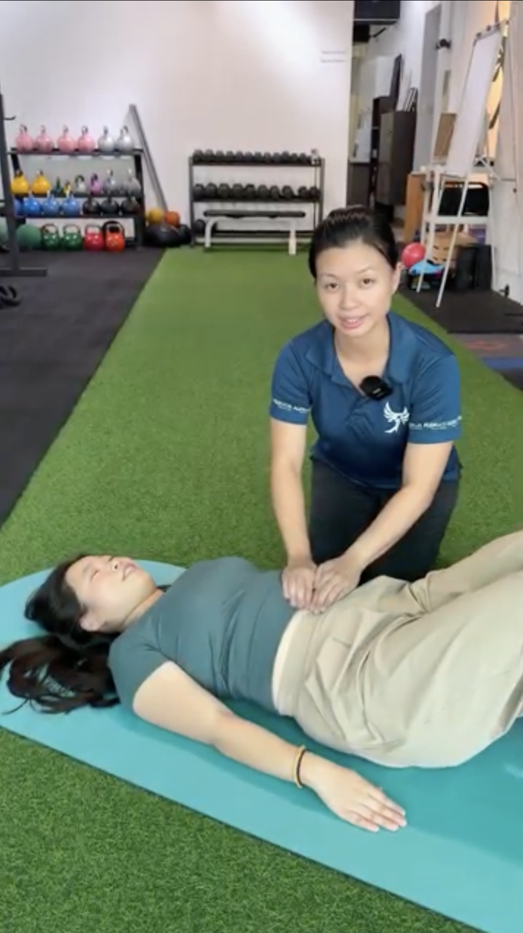 Lavinia guiding Lily through a core exercise on a mat
